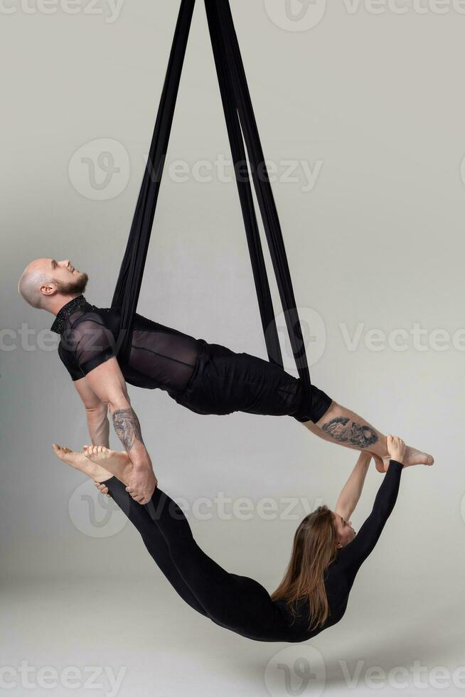 hermosa niña y un atlético hombre en un negro deporte trajes son ejecutando un acrobático elementos en un estudio. foto
