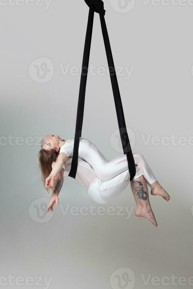 hermosa niña y un atlético hombre en un blanco deporte trajes son ejecutando un acrobático elementos en un estudio. foto