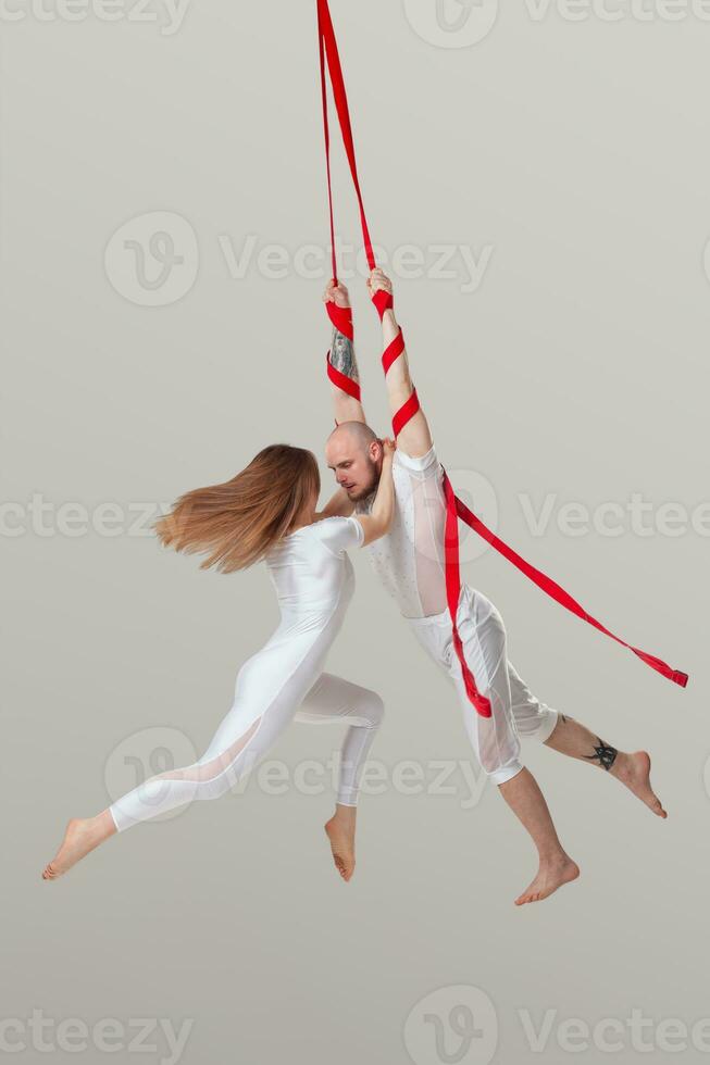 hermosa niña y un atlético hombre en un blanco deporte trajes son ejecutando un acrobático elementos en un estudio. foto