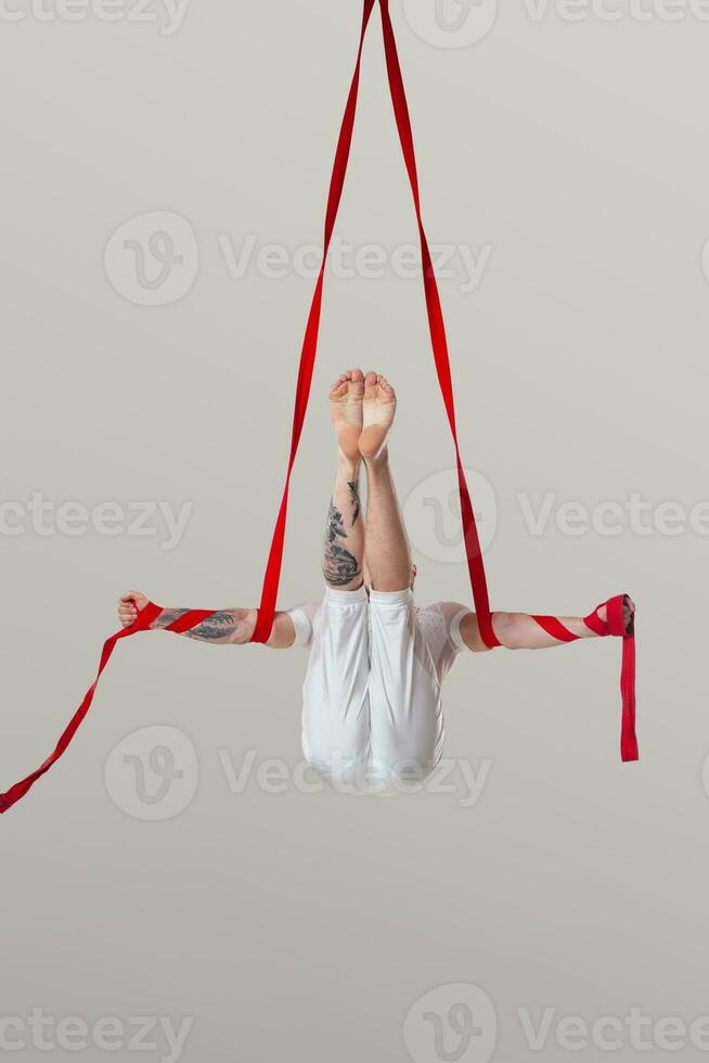 Athletic man in a white sport suit is performing an acrobatic elements in a studio. photo