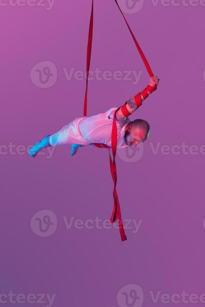 Athletic man in a white sport suit is performing an acrobatic elements in a studio. photo