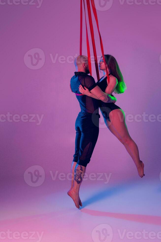 hermosa niña y un atlético hombre en un negro deporte trajes son ejecutando un acrobático elementos en un estudio. foto