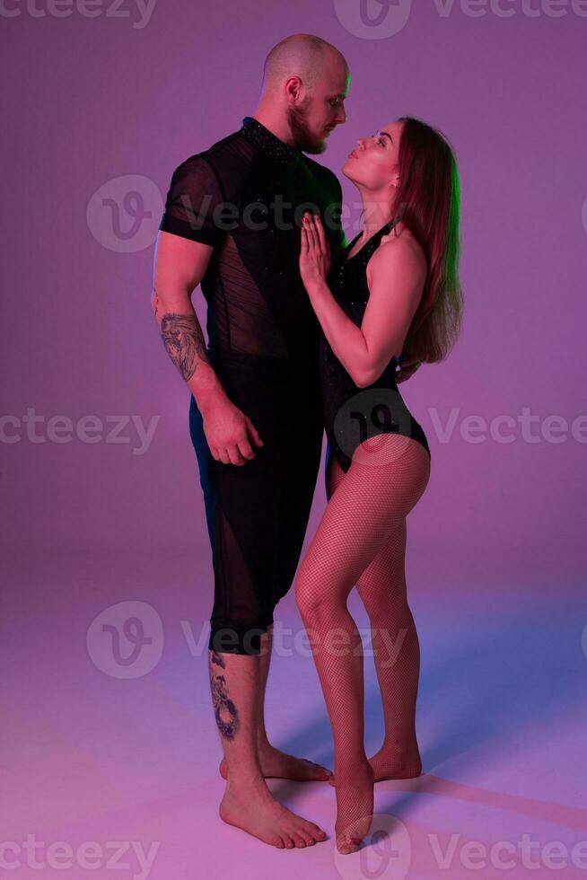 atlético gimnastas en un negro deporte trajes son posando en un estudio. foto