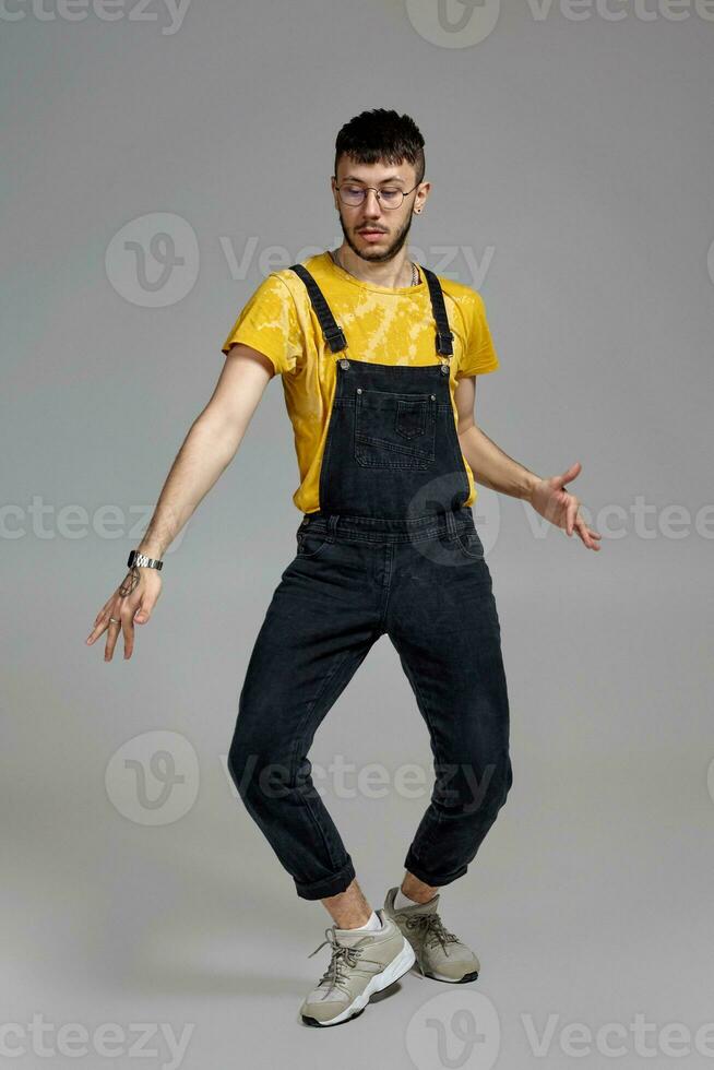 Full-length portrait of a funny guy dancing in studio on a gray background. photo