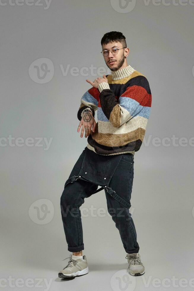 Full-length portrait of a funny guy dancing in studio on a gray background. photo