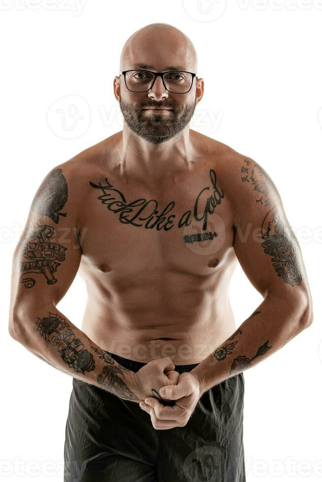 Athletic bald, tattooed man in black shorts is posing isolated on white background. Close-up portrait. photo