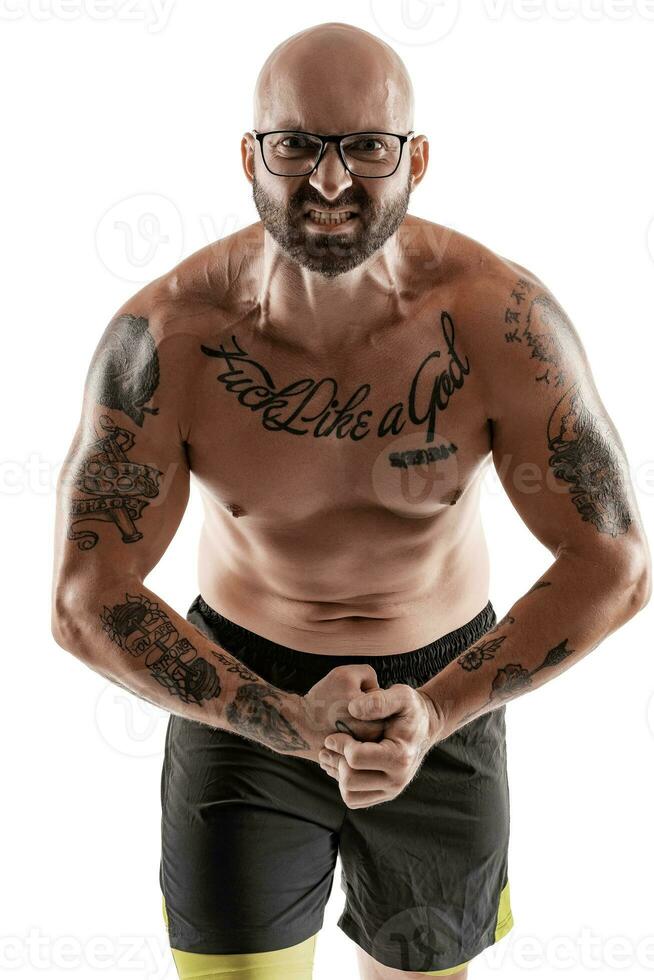 Athletic bald, tattooed man in black shorts is posing isolated on white background. Close-up portrait. photo