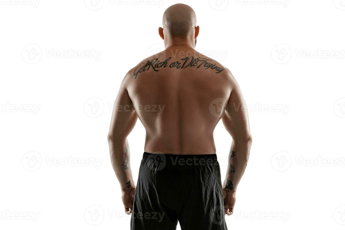 Athletic bald, tattooed man in black shorts is posing isolated on white background. Close-up portrait. photo