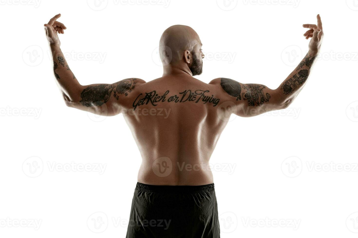 Athletic bald, tattooed man in black shorts is posing isolated on white background. Close-up portrait. photo