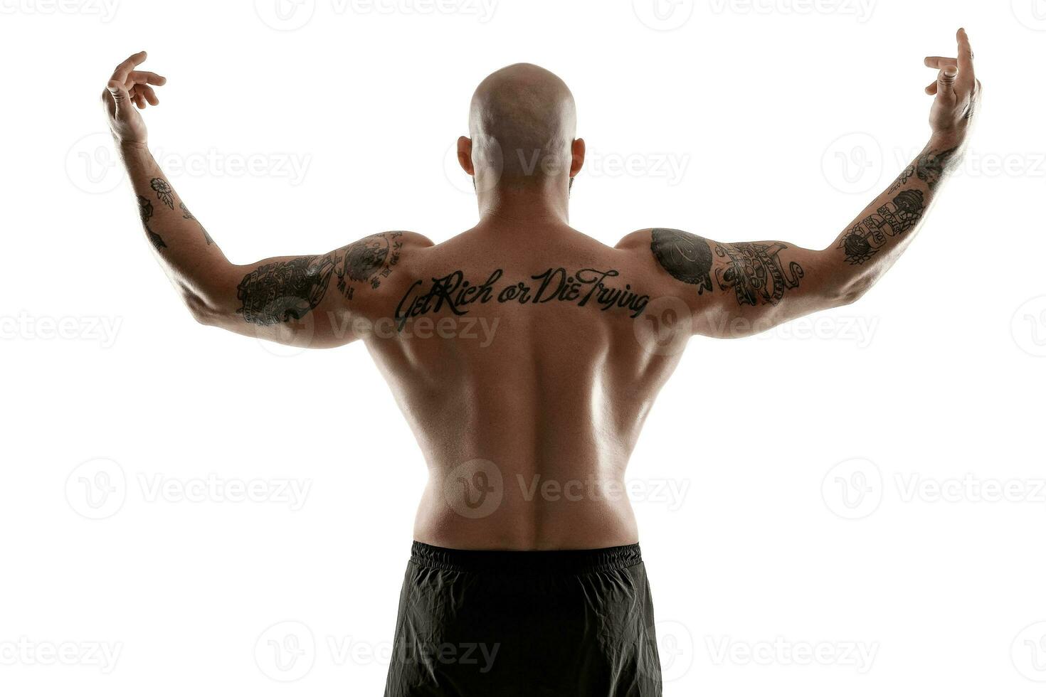 Athletic bald, tattooed man in black shorts is posing isolated on white background. Close-up portrait. photo