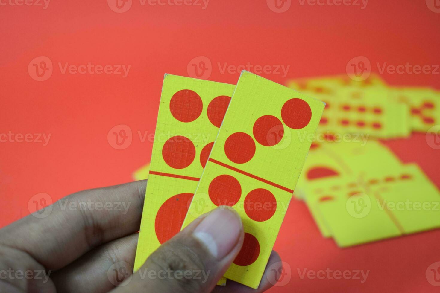 hand hold dominoes playing cards isolated red background, yellow red dominoes cards photo