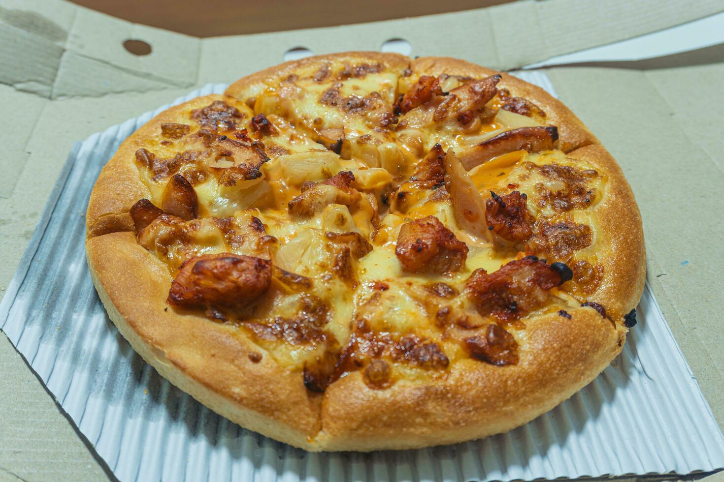 Close up of a hot sausage and cheese pizza in a cardboard box. Pizza delivery. Pizza menu. Thai style pizza. photo