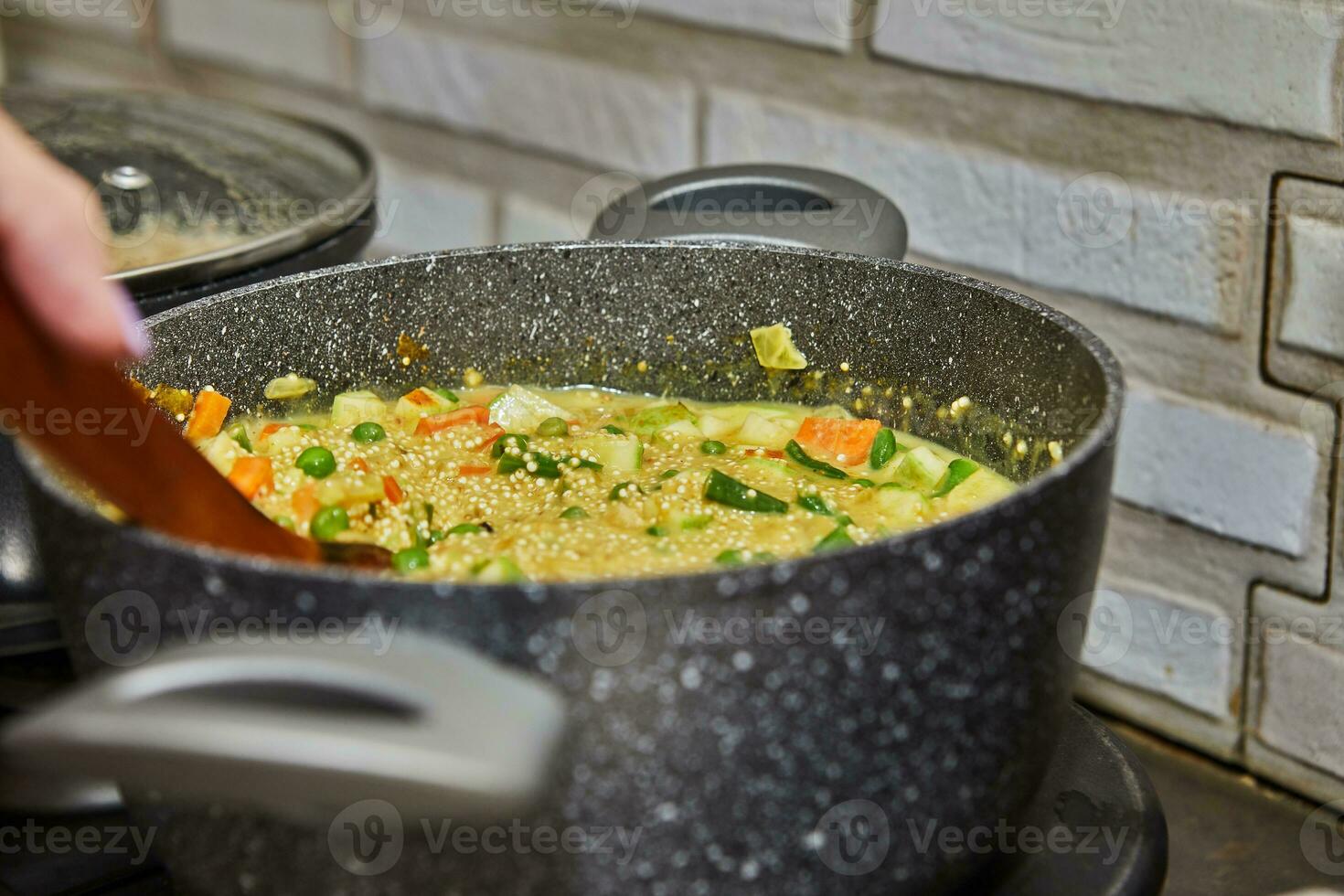 Chef Cooking Delicious Couscous Soup with Fresh Greens on Gas Stove photo