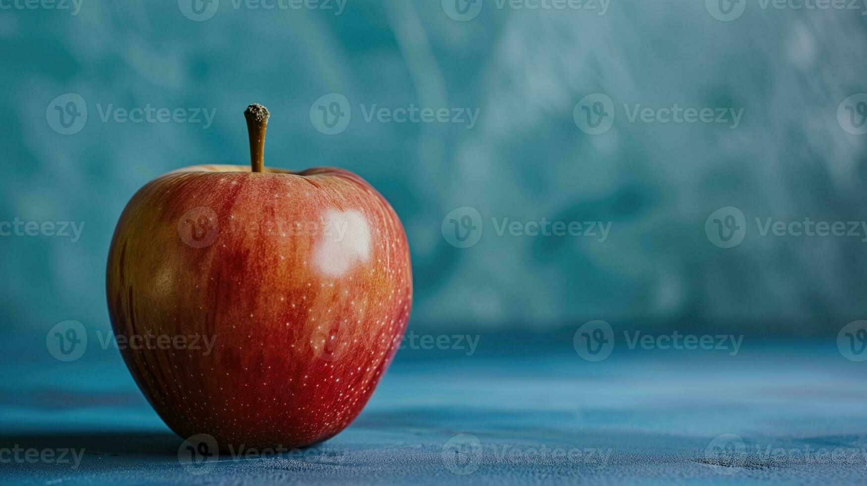 AI generated Red apple with stem on a textured blue background photo
