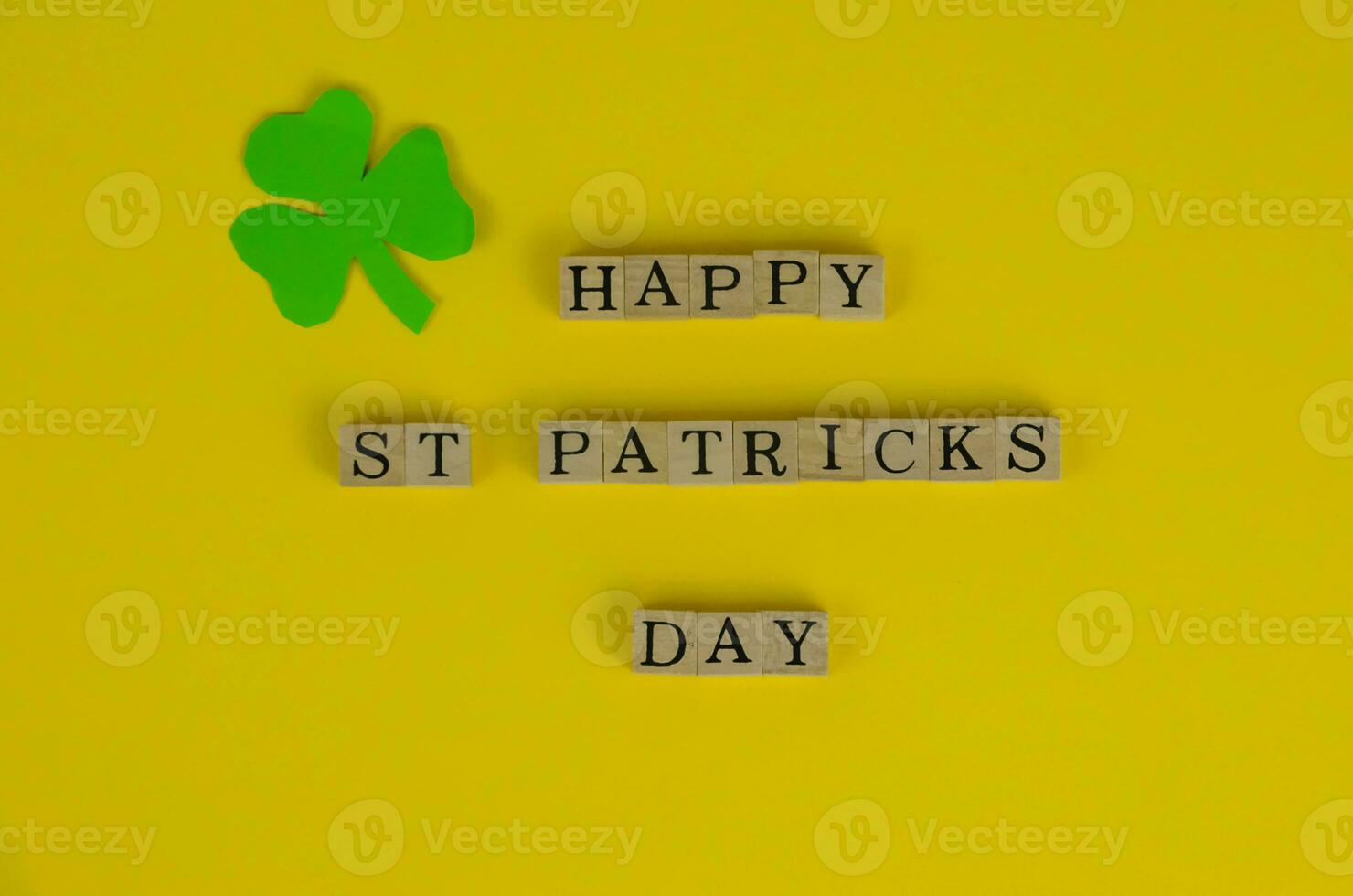 Happy St. Patrick's Day Words on Yellow Background With Three-Leaf Clover Leaf photo