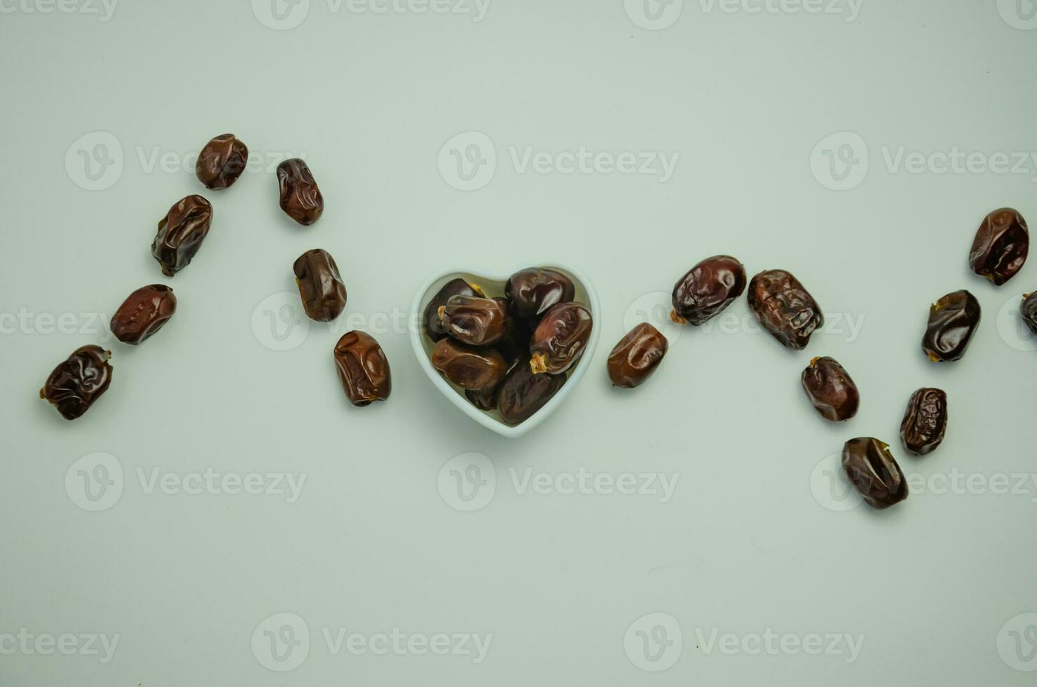Dates lie in a white plate in the shape of a heart and laid out heart rate, healthy food concept photo