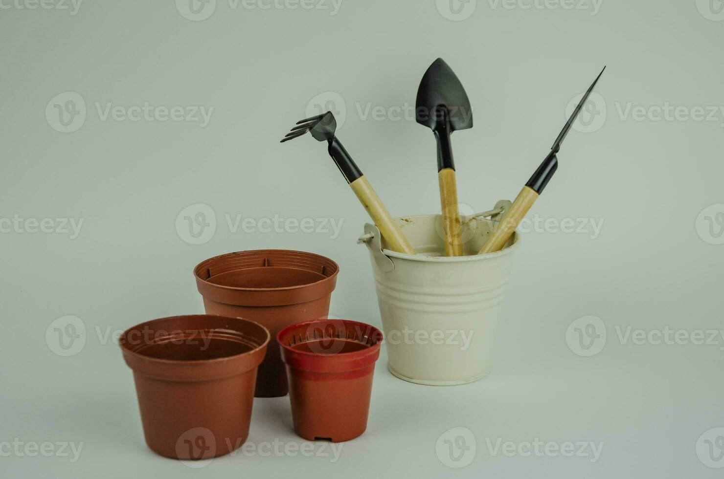 garden objects on a light background, watering can pots for planting, shovels with rakes for working in the garden and vegetable garden. High quality photo