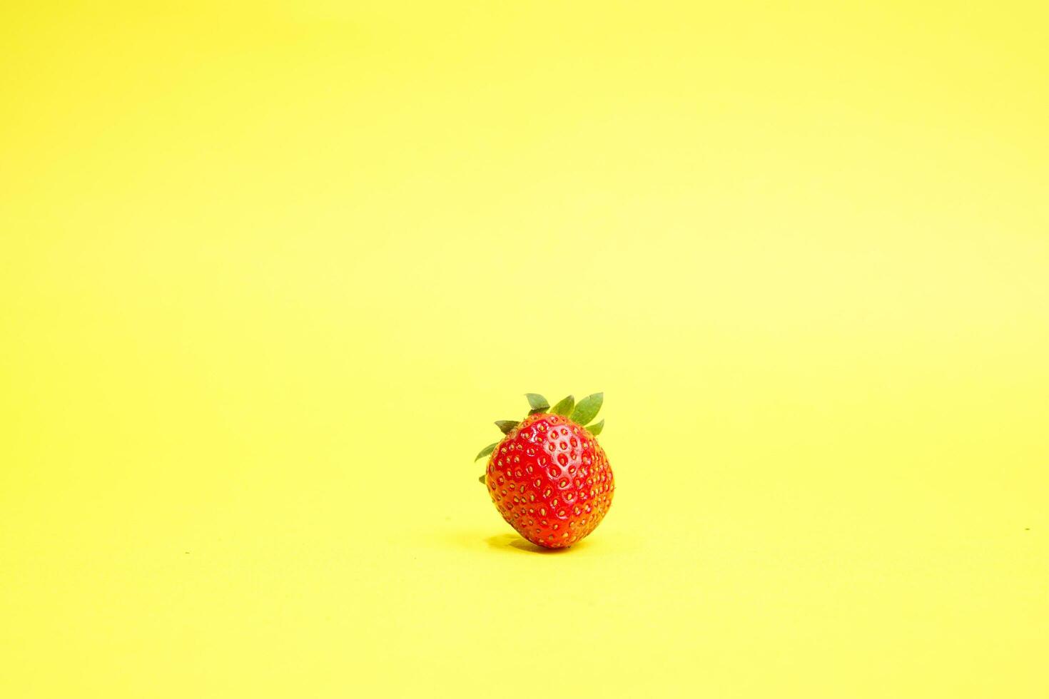 Single strawberry isolated on yellow background photo