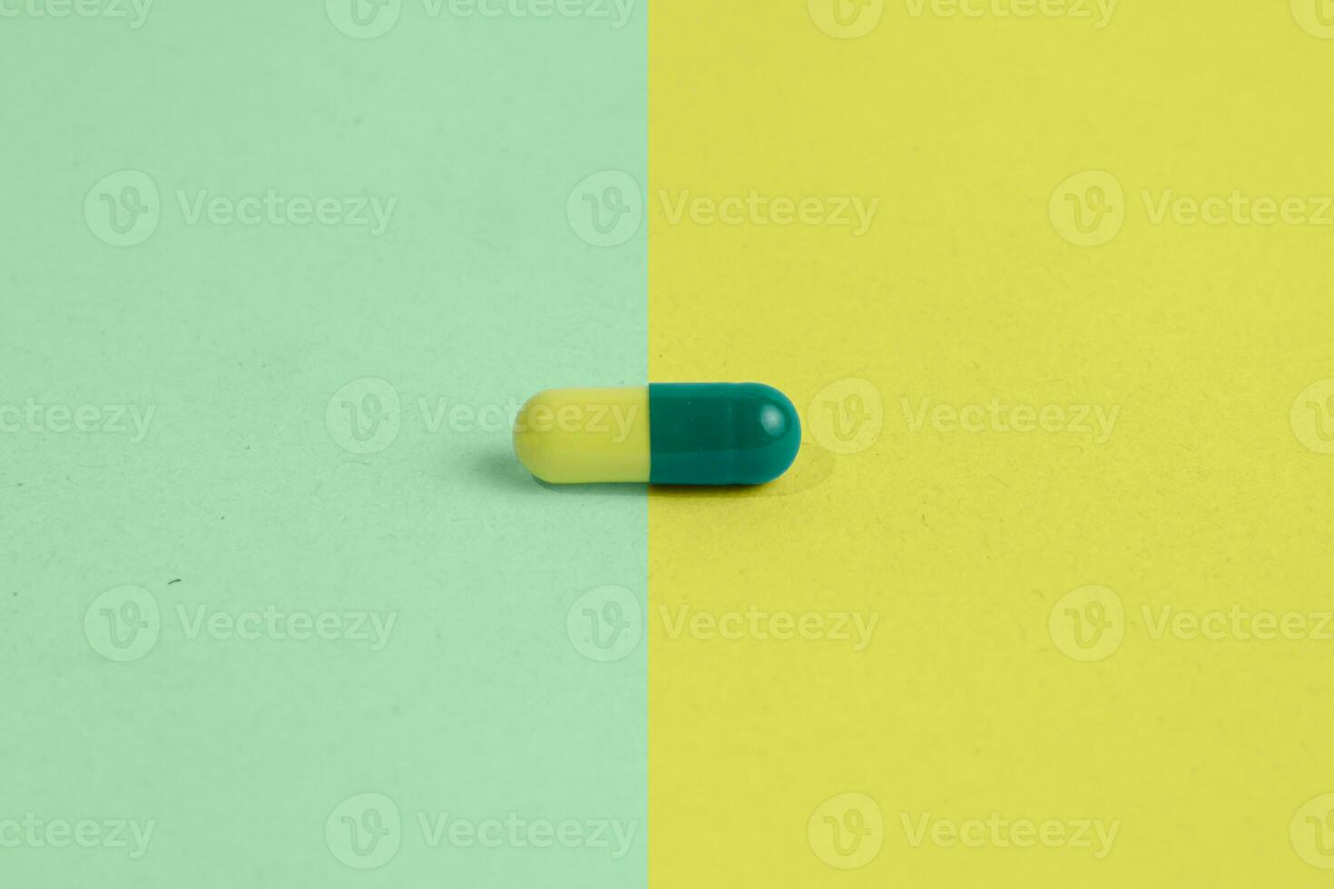 dual color green and yellow capsules with a matching color background photo
