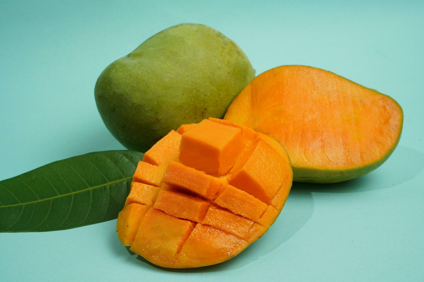 fresh mango fruit with cube slice with yellow flesh inside isolated on cutting board blue background contain vitamin C photo