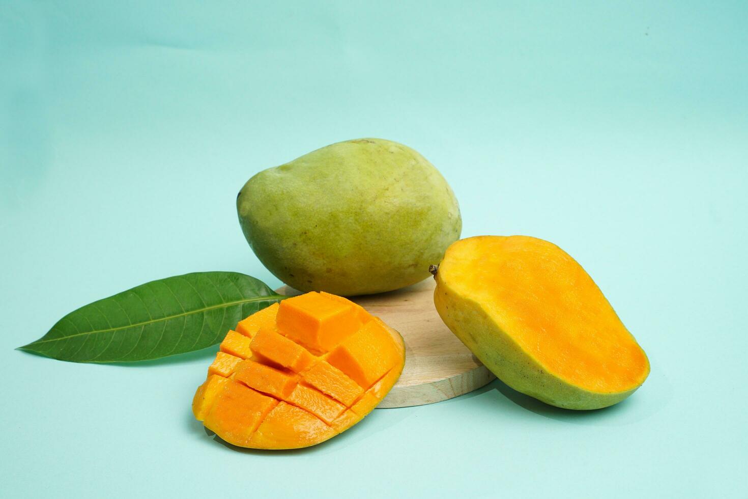 fresh mango fruit with cube slice with yellow flesh inside isolated on cutting board blue background contain vitamin C photo