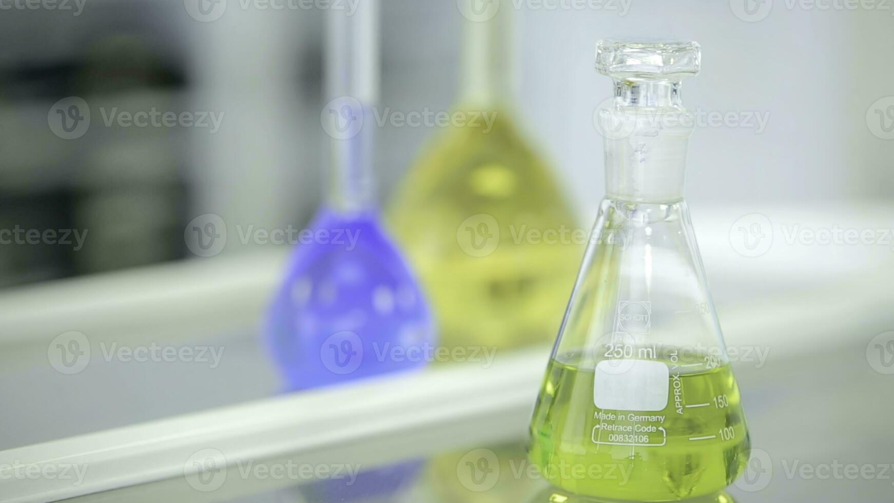 Chemical flasks with green and blue liquid on white background. Test-tubes with colorful chemical reagent. Laboratory glassware. Chemical Laboratory. Selective cocus. Bokeh. scientist and medical photo