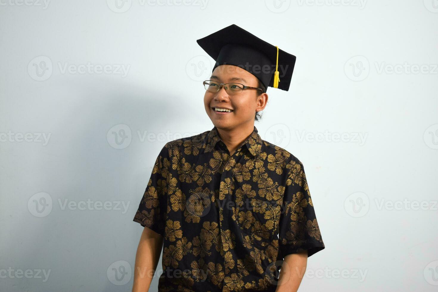 Expressive of Adult indonesia male wear batik, toga cup or graduation hat and eyeglasses isolated on white background, expressions of portrait graduation photo