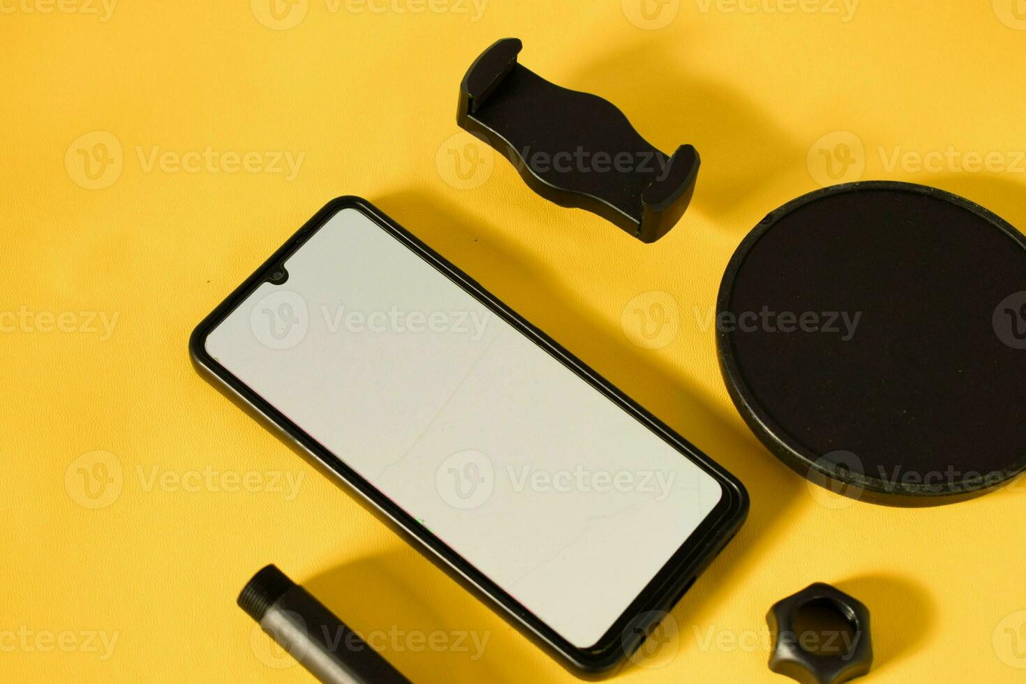 top view of smartphone with white screen and parts of stand phone or mini tripod photo