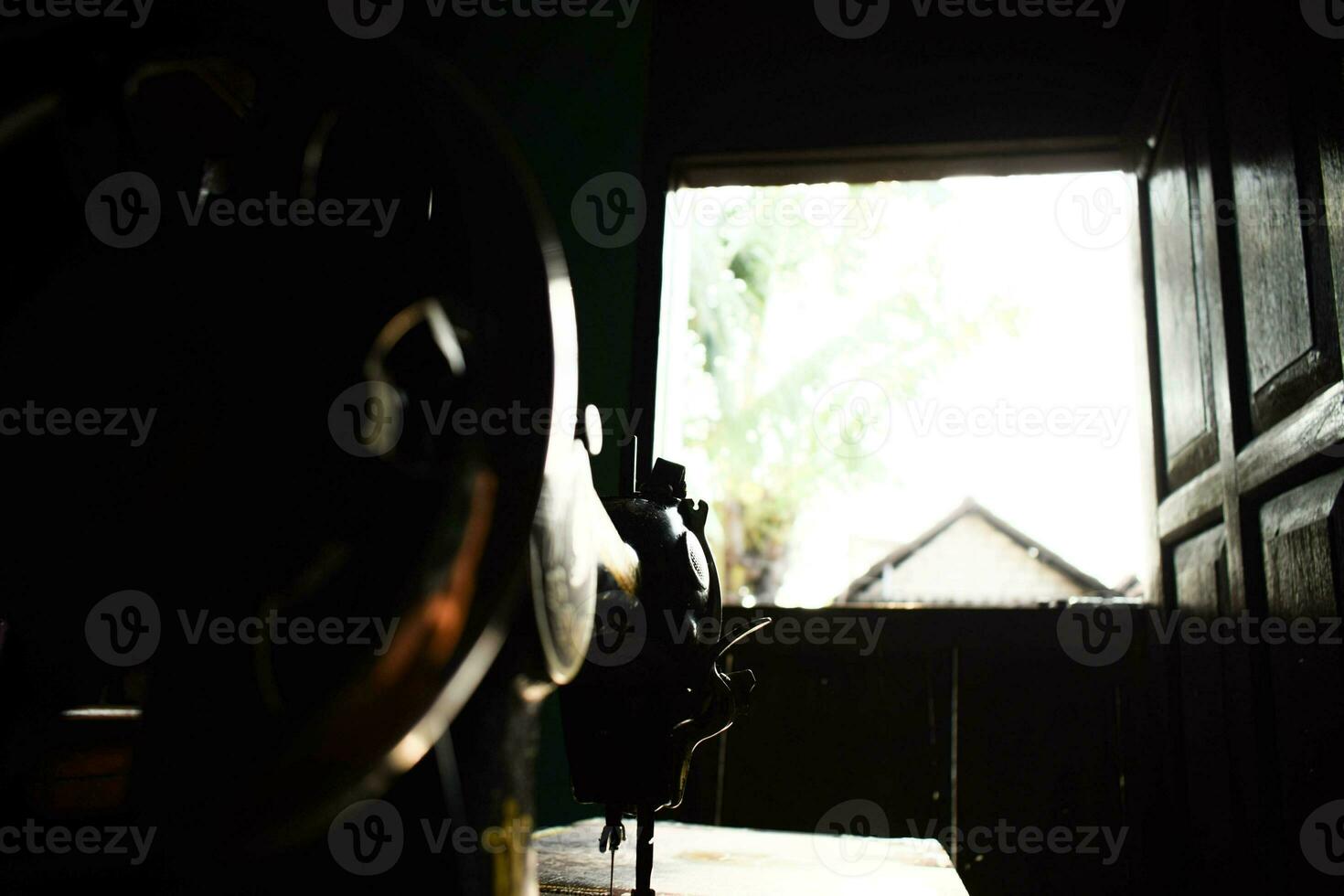 wheel of antique sewing machine wheel with sunlight on table wood photo