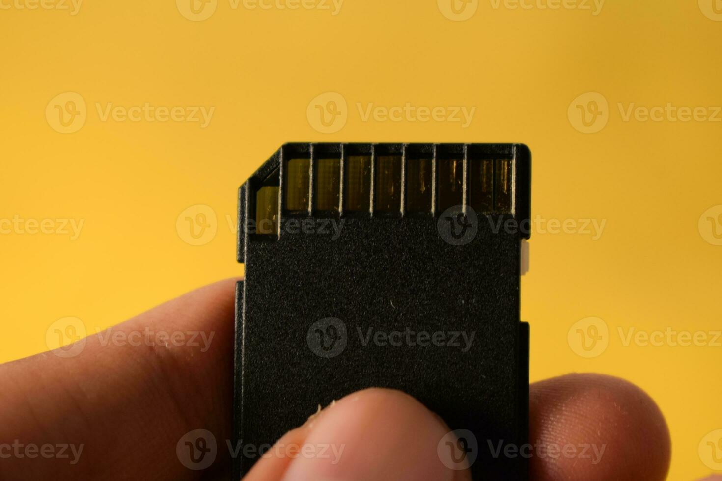 Close up hand holds SD Card for DSLR or Mirrorless camera on yellow background photo