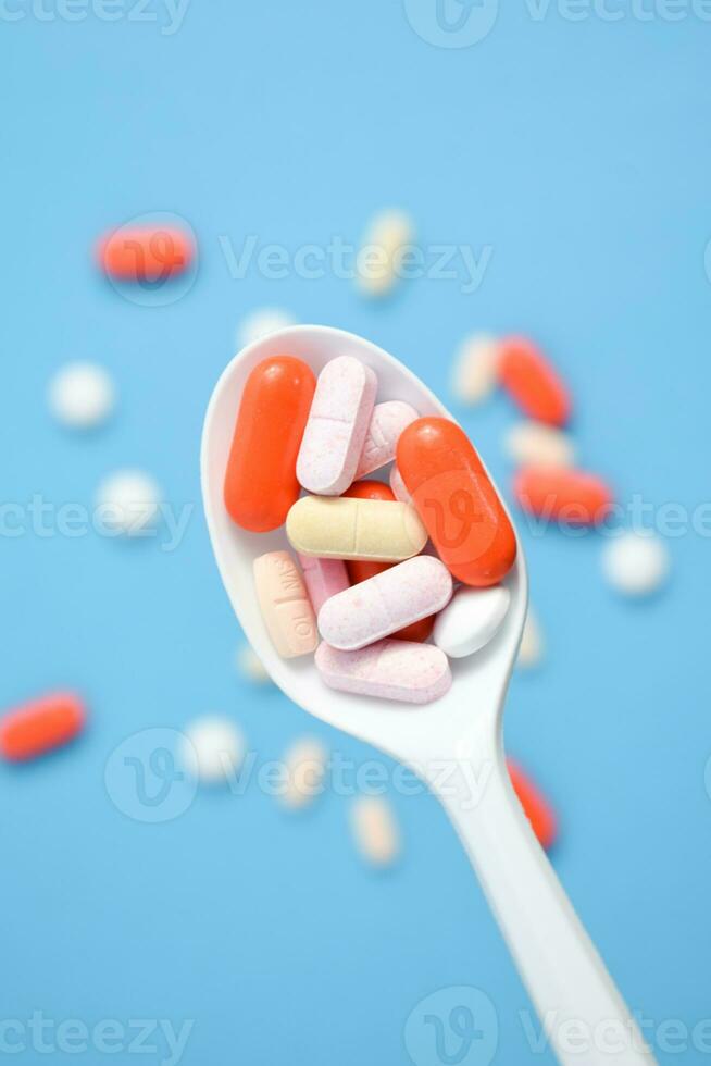 Colorful Medicine Pills in White spoon on blue background, supplement, vitamin, colorful photo