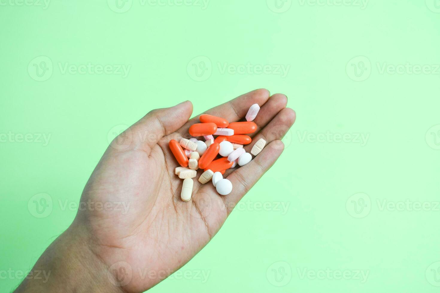 Colorful Medicine pills in man hand on gree background photo