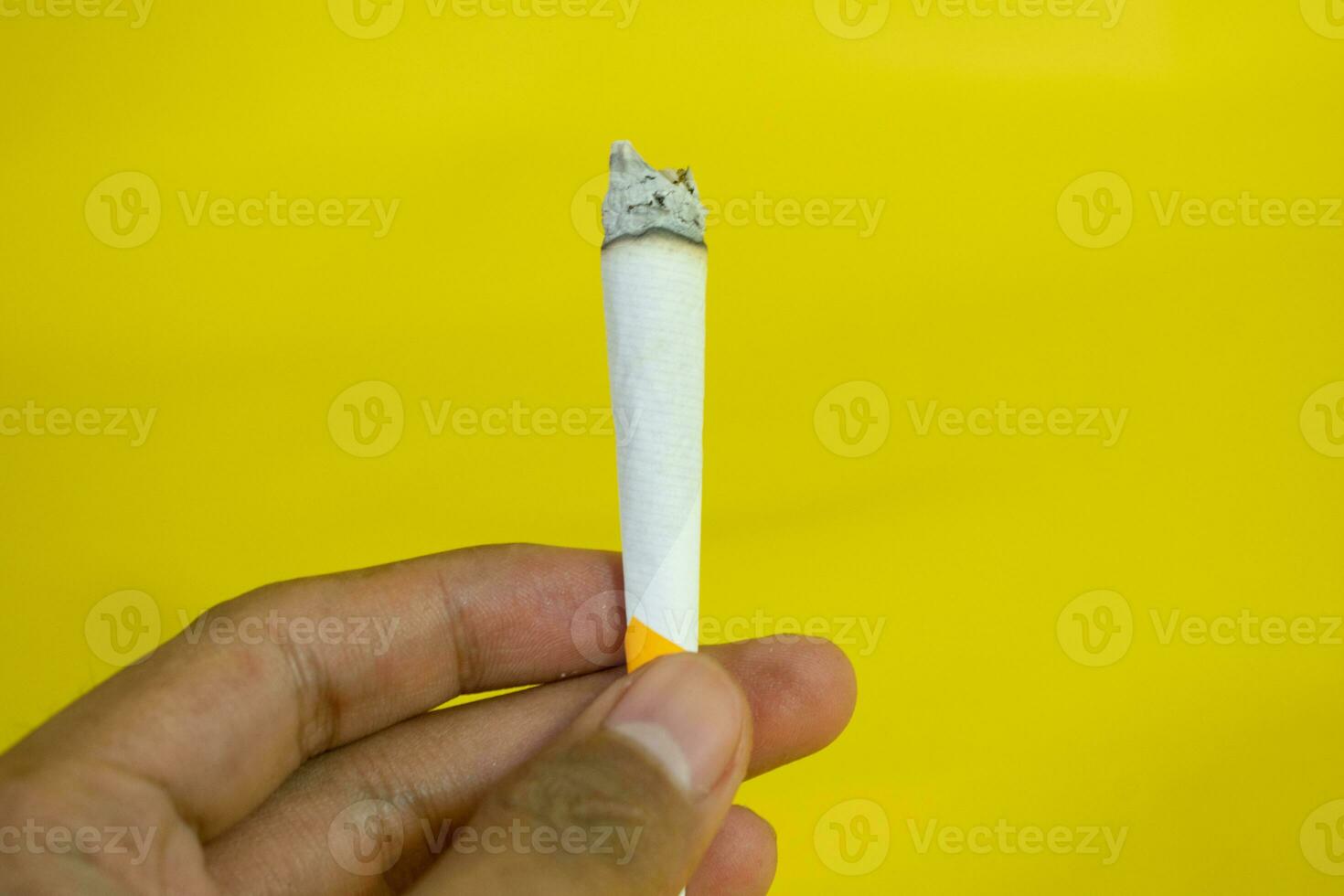 un hombre mano sostiene un hecho a mano cigarrillo en amarillo antecedentes foto
