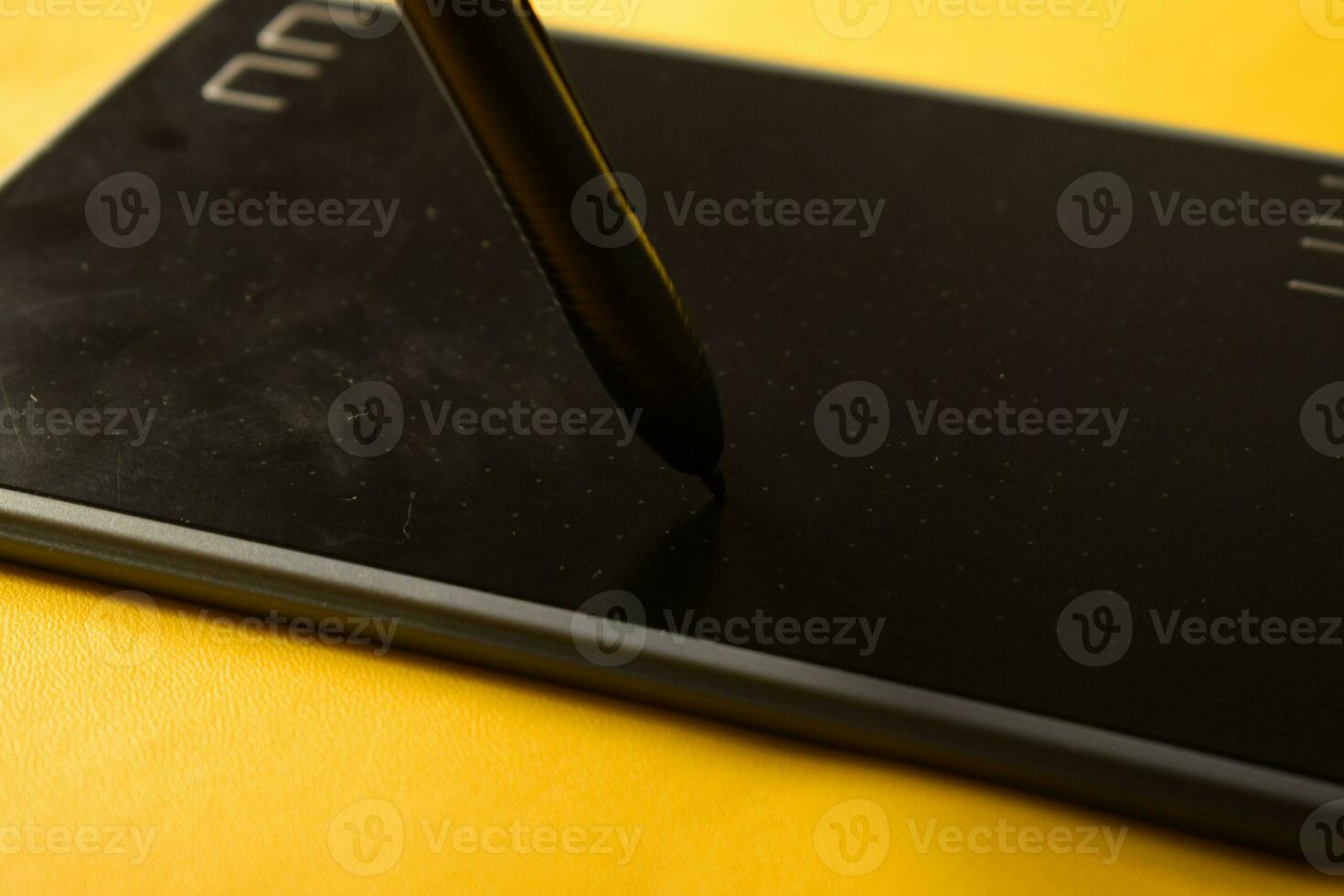 Electronic drawing pen tablet  and stylus close up isolated yellow photo