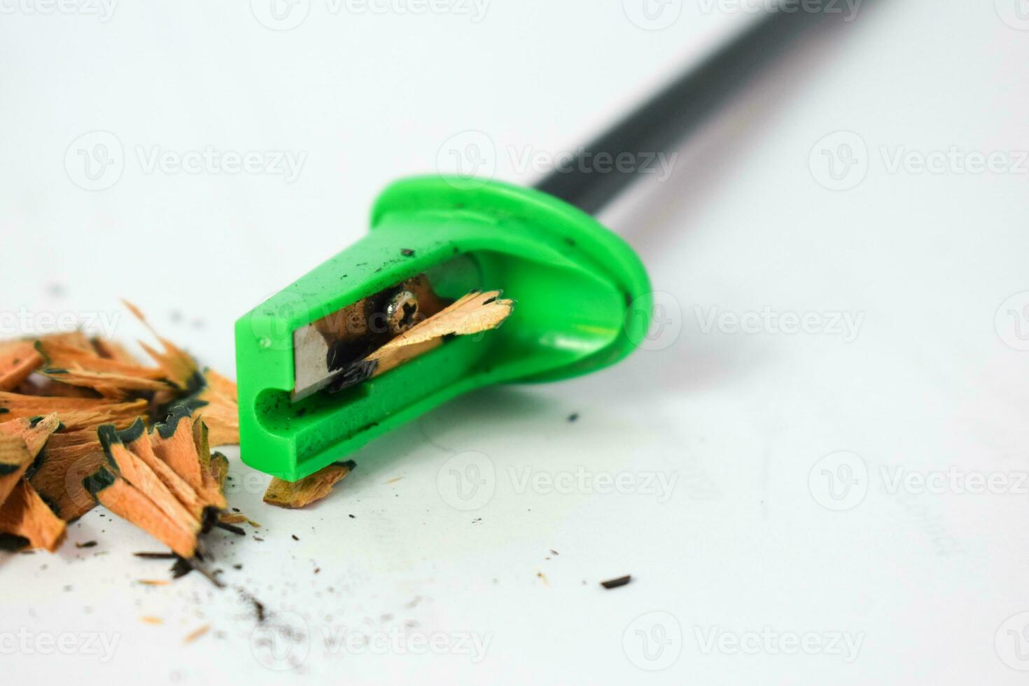 green pencil sharpener and dark green pencils, pencil shavings on white background photo