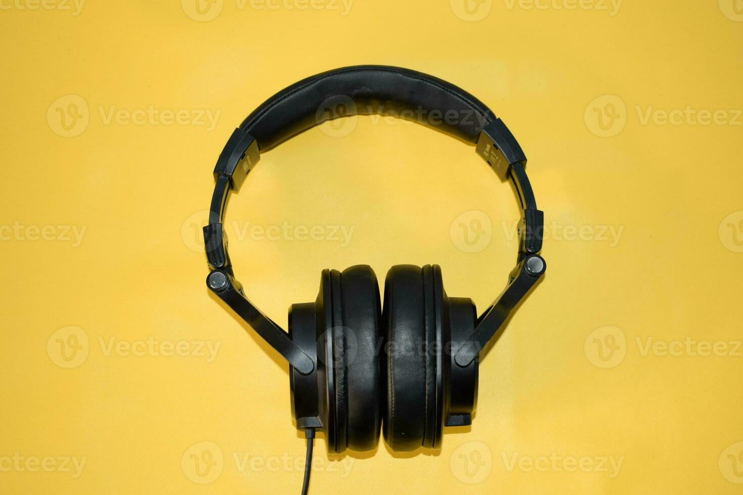 top view black headphone with cable on yellow background photo