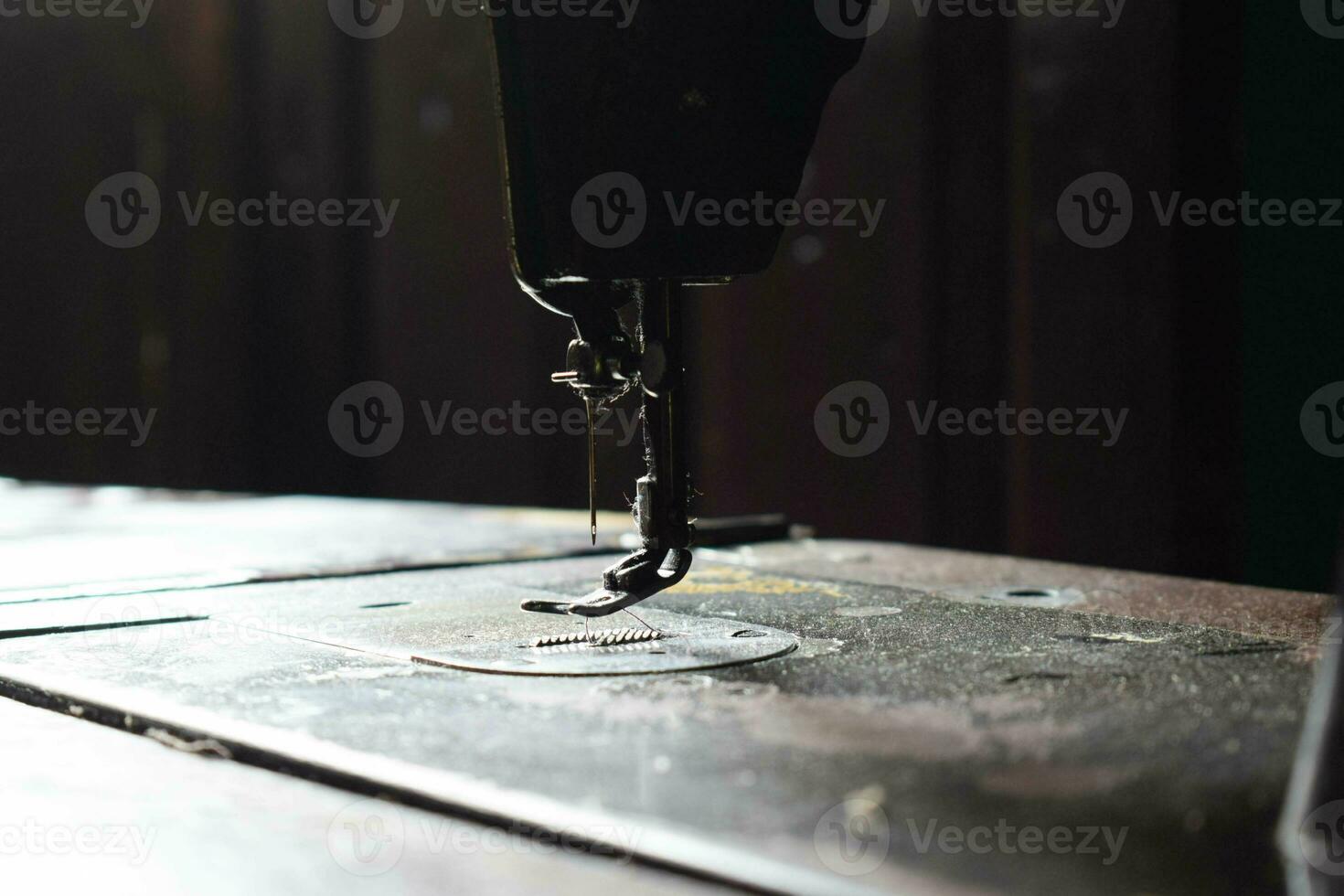 Close up sewing machine with needle on wood table, antique sewing machine with dust photo