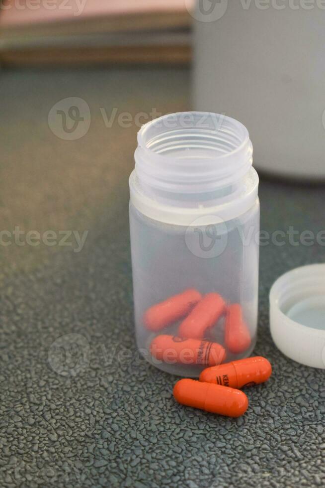 medical pill capsule and bottle with mug or glas of water on table workspace photo