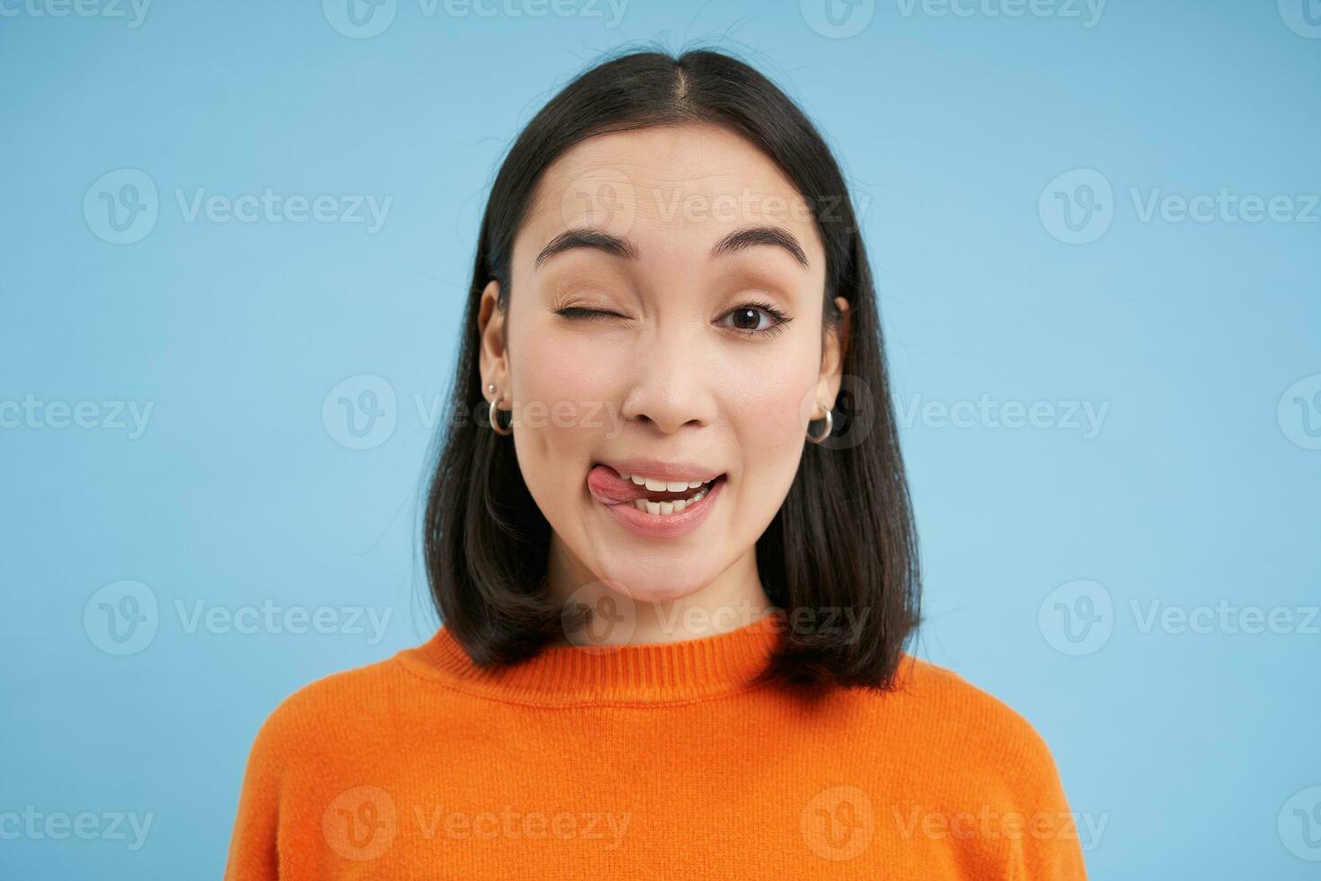 Close up of candid young female model laughs and smiles, shows natural happy emotions, stands over blue background photo