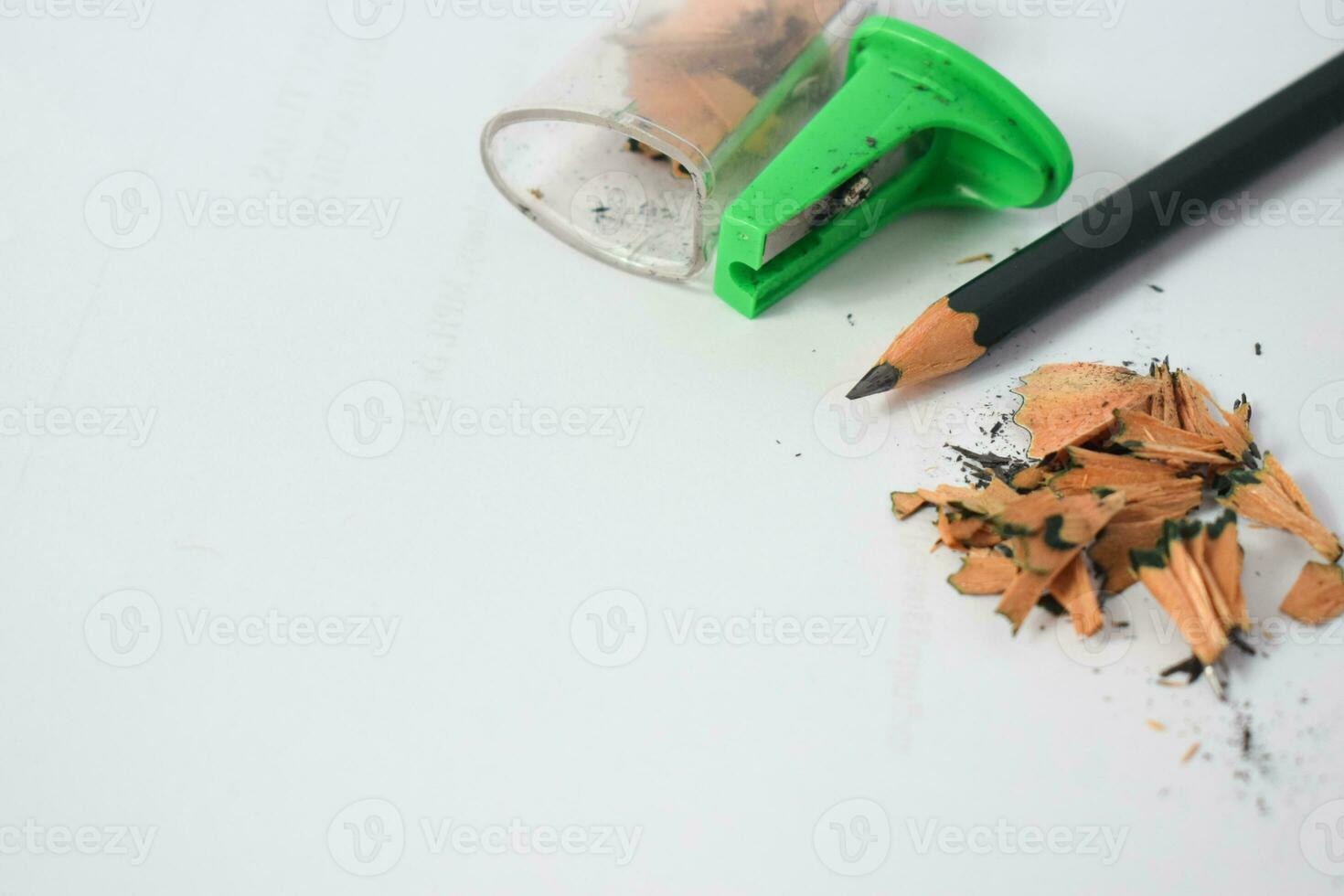 green pencil sharpener and dark green pencils, pencil shavings on white background photo