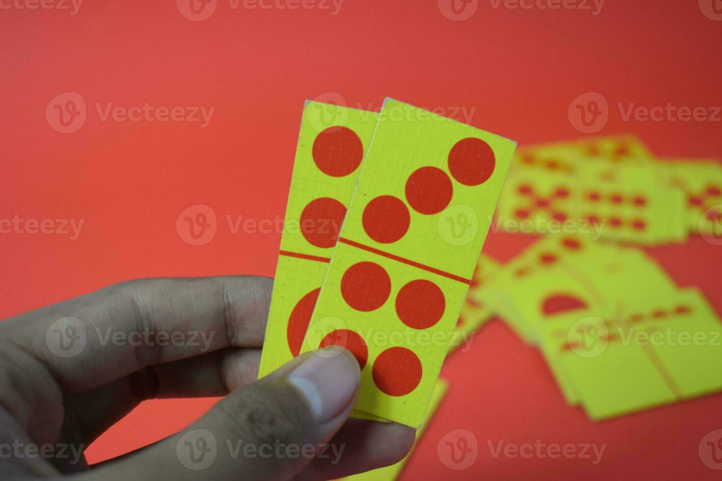 hand hold dominoes playing cards isolated red background, yellow red dominoes cards photo