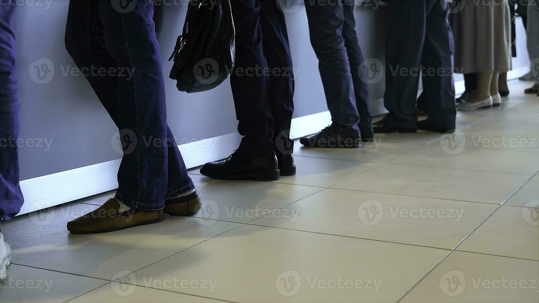 View of legs of customers standing n the modern office, getting served in the bank. Media. People are queuing for service in the department of a bank. photo