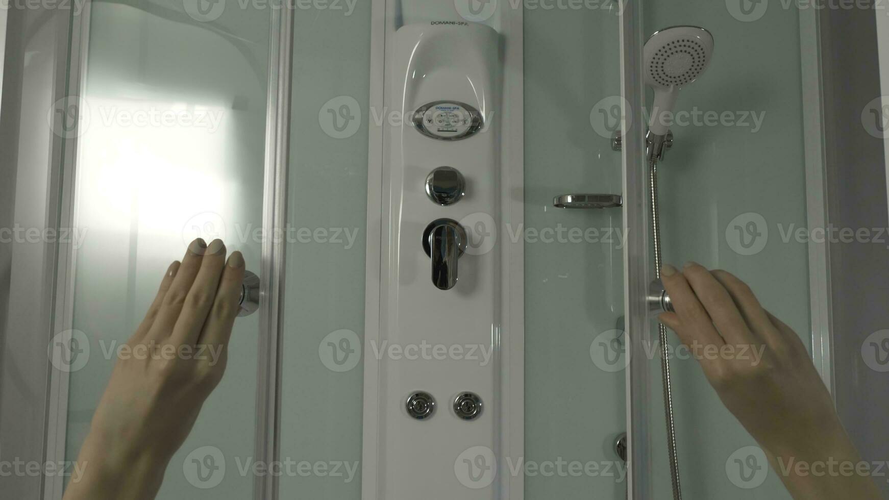 Woman's hands opens the door in the shower. Modern shower cabin with a large number of devices photo