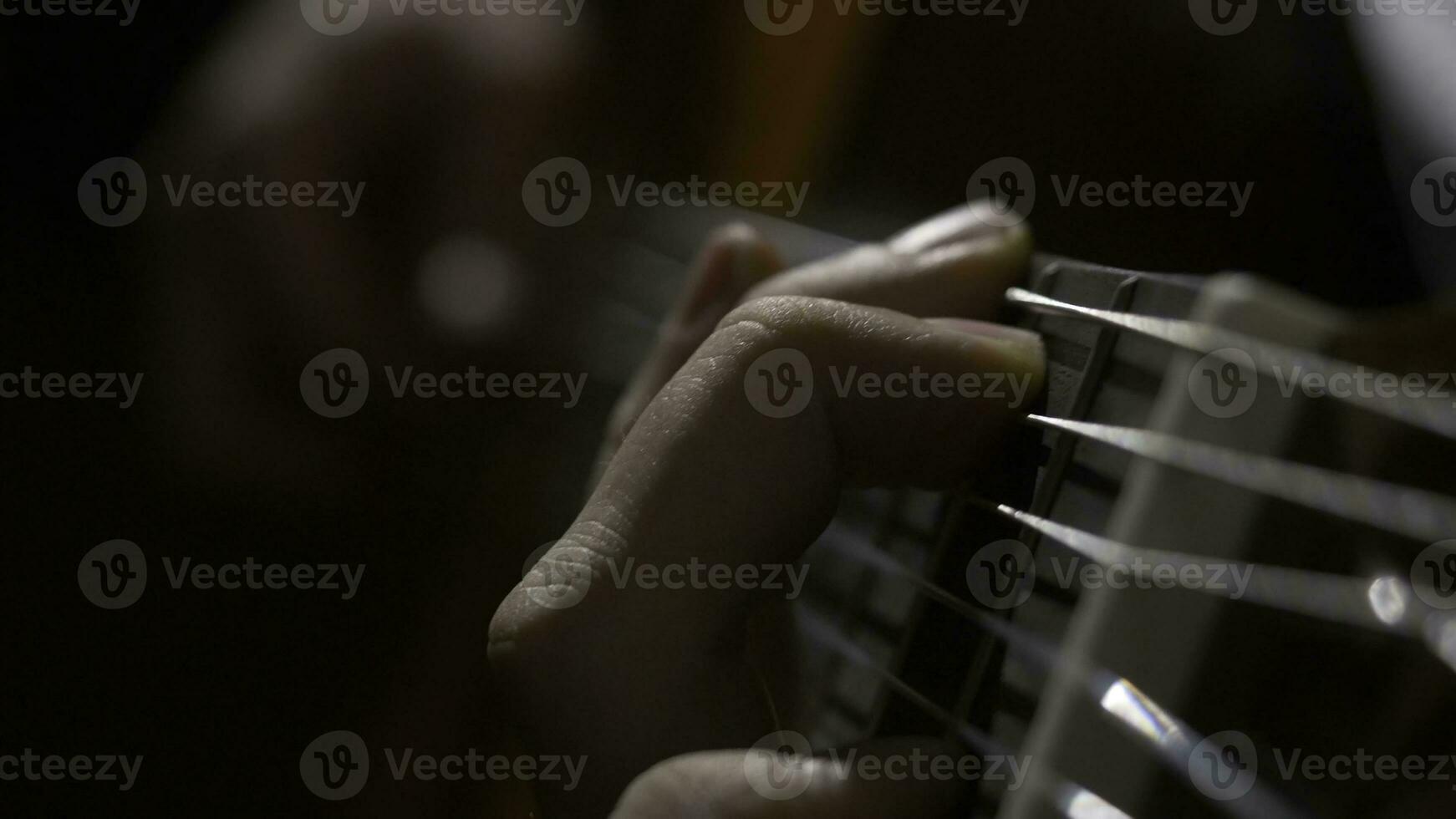 Close up of guitarist hand playing acoustic guitar. Close up shot of a man with his fingers on the frets of a guitar playing photo