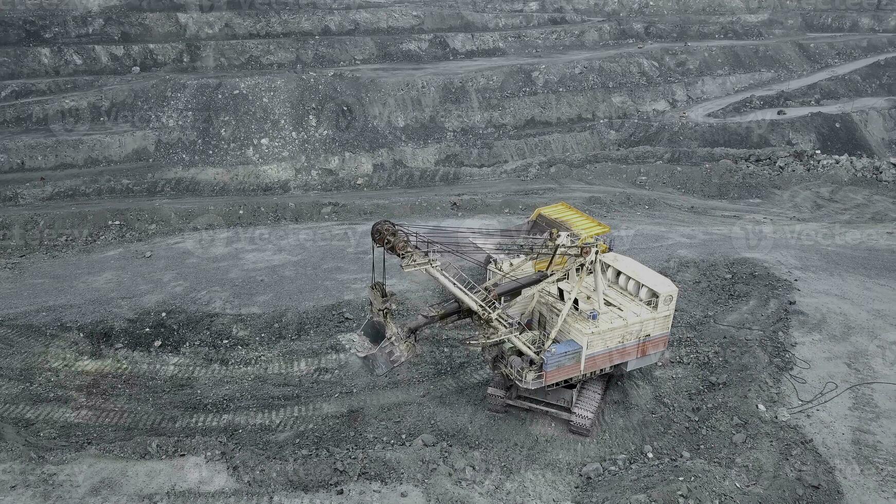 Top view of excavator in open pit. Excavator falls asleep rubble in dumper on outdoor quarry in extraction of minerals. Concept of extraction of minerals photo