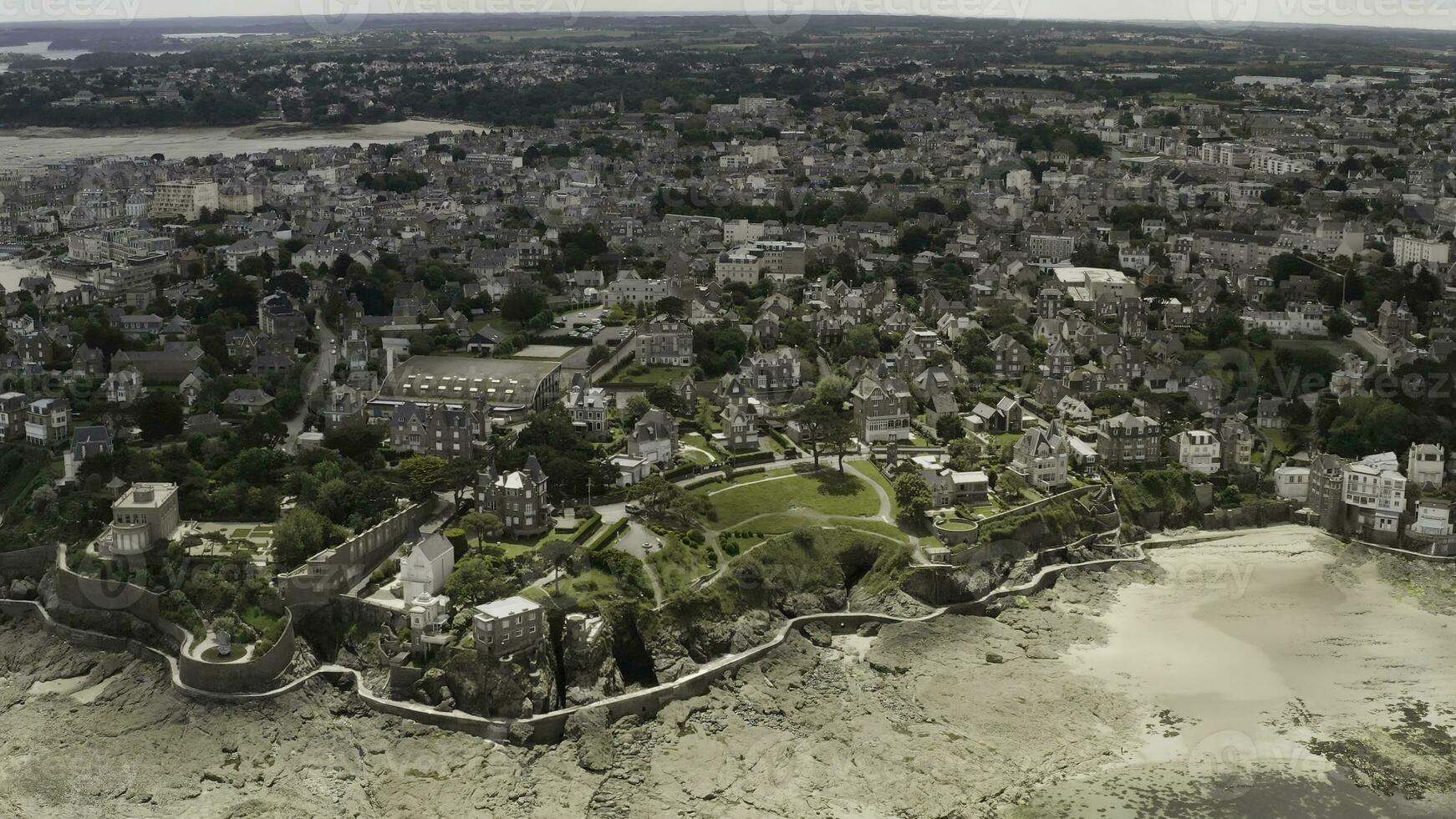 Aerial wonderful view of a city with many greenery and beautiful architecture located near the sea shore. Action. Coastal city and blue sea in a summer time. photo