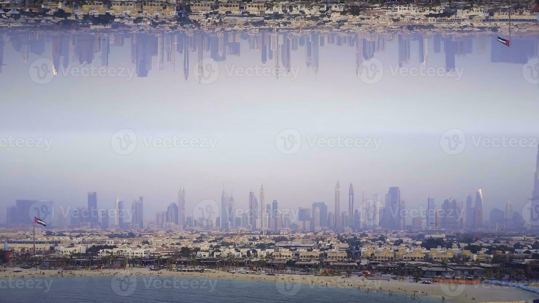 Aerial view of sandy coast, beautiful sea on modern skyscrapers background, mirror horizon effect. Stock footage. Beautiful beach with the city modern buildings behind, inception theme. photo