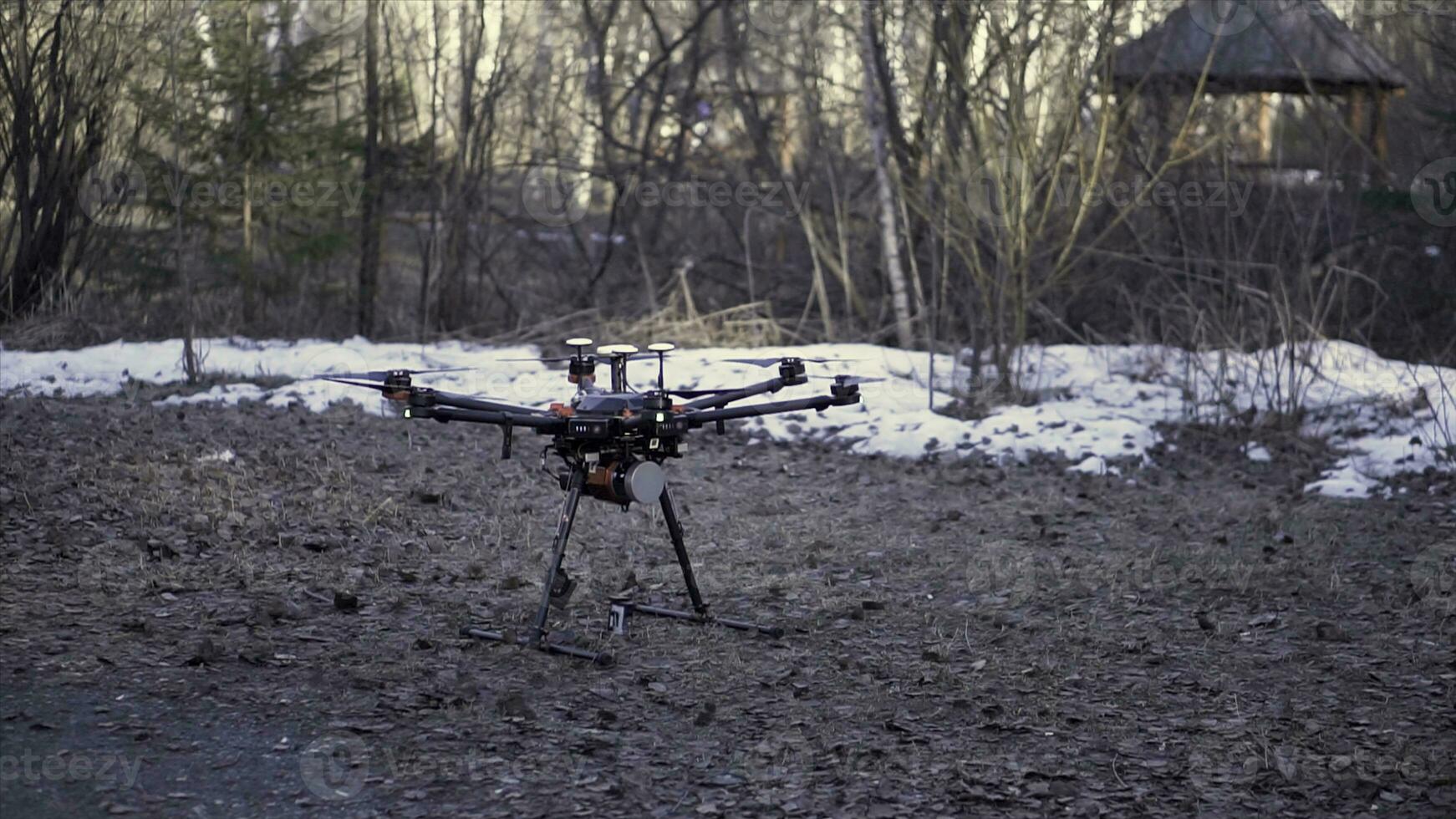 Close up for black drone standing on the ground before the flight, aerial video and photo shooting concept. Clip. Quadcopter starting to rotate its blades and taking off.