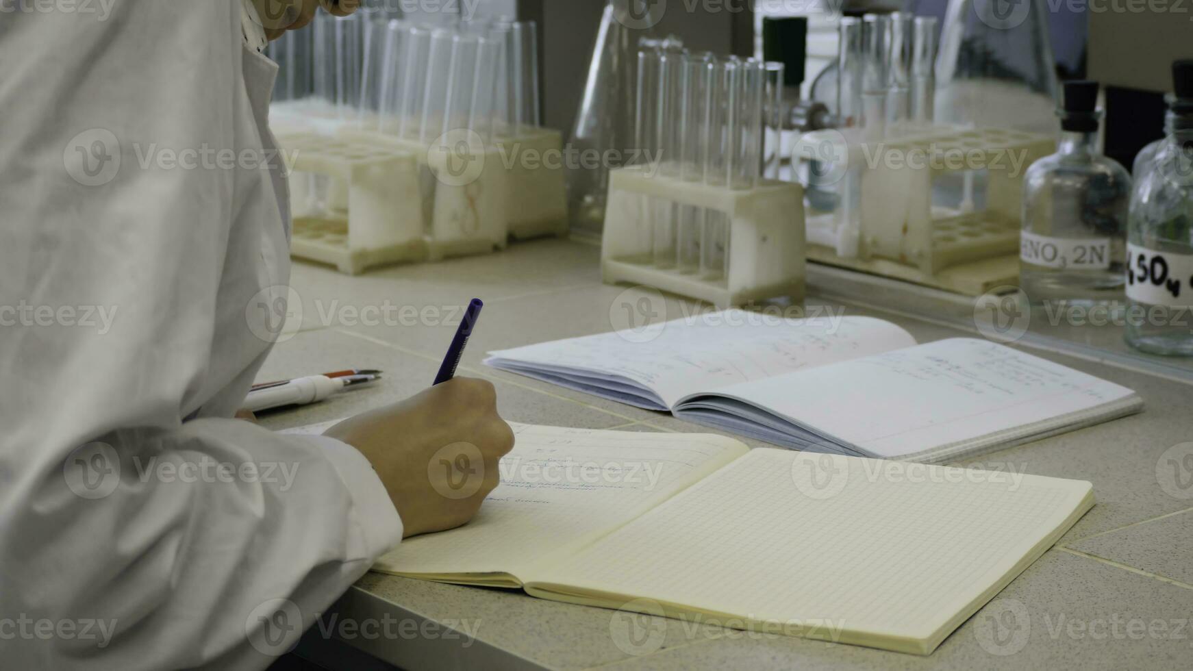 joven científico médico tomando notas hembra científico toma notas en el antecedentes son el tubos foto