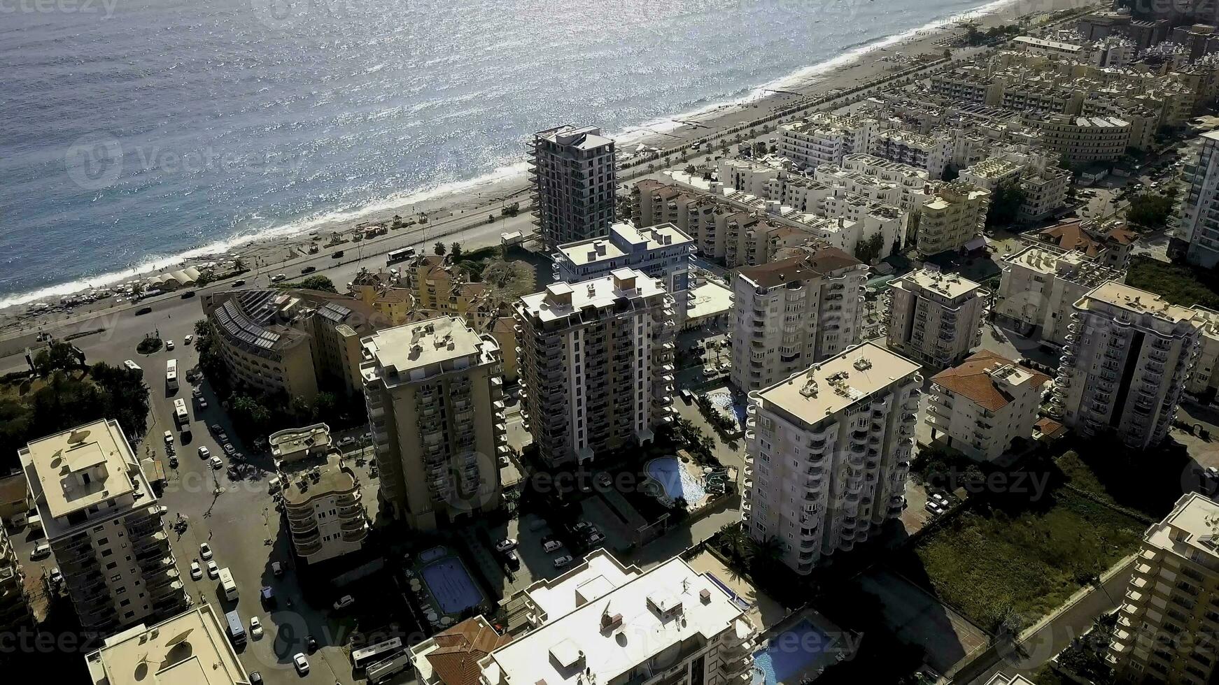 Top view of beautiful big city by sea on background of mountains. Clip. Panorama of southern resort town located on coast of blue sea and mountain landscape photo